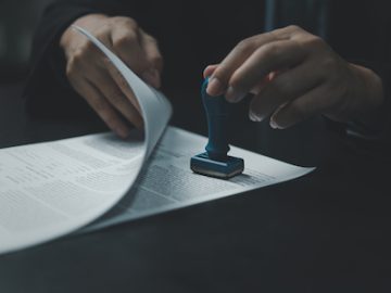 Man stamping approval of work finance banking or investment marketing documents on desk.